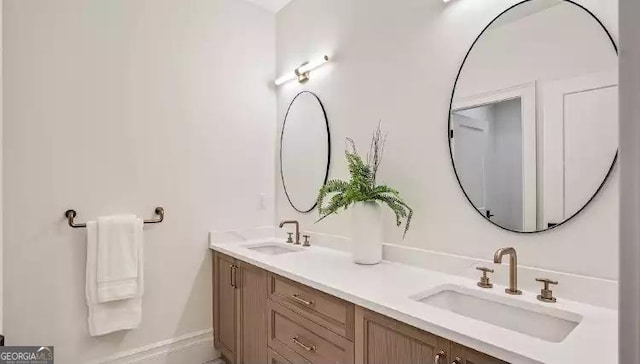 full bathroom with a sink, baseboards, and double vanity