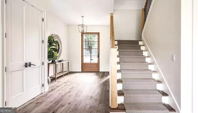 foyer with stairway, wood finished floors, and baseboards