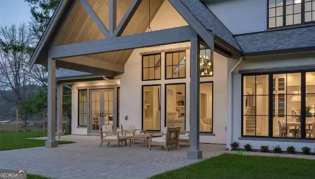 rear view of property with stucco siding, a shingled roof, a patio area, and french doors