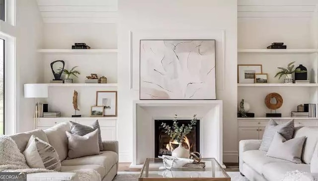 living area with a warm lit fireplace and built in shelves