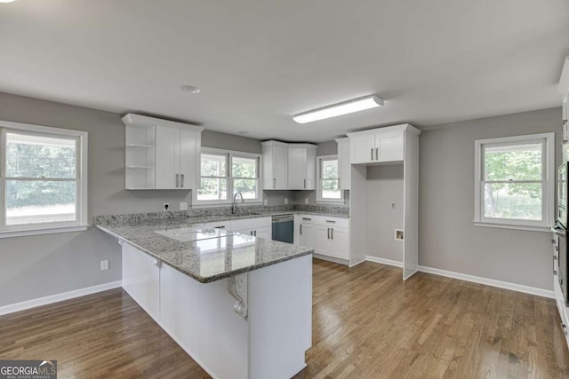 kitchen with white cabinets, a peninsula, white cooktop, light stone countertops, and stainless steel dishwasher