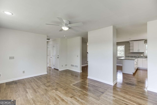 unfurnished living room with baseboards, ceiling fan, and light wood-style floors