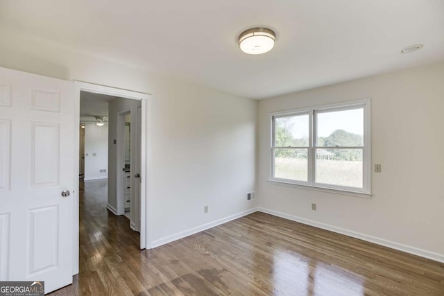 spare room featuring visible vents, baseboards, and wood finished floors