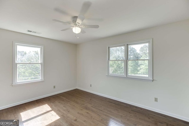 spare room featuring visible vents, ceiling fan, baseboards, and wood finished floors