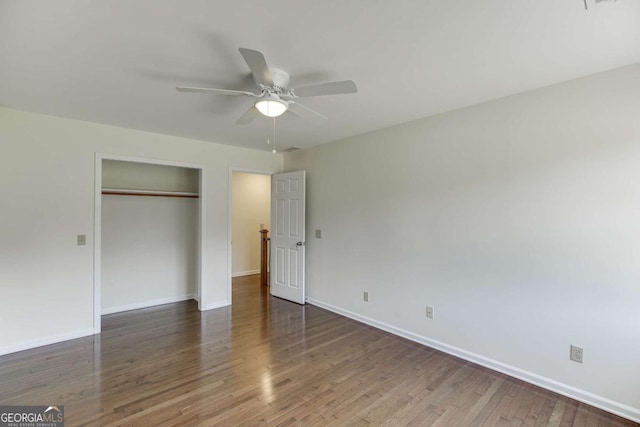 unfurnished bedroom with a closet, wood finished floors, a ceiling fan, and baseboards