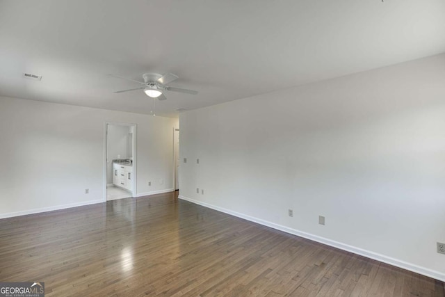 unfurnished room with a ceiling fan, visible vents, baseboards, and wood finished floors