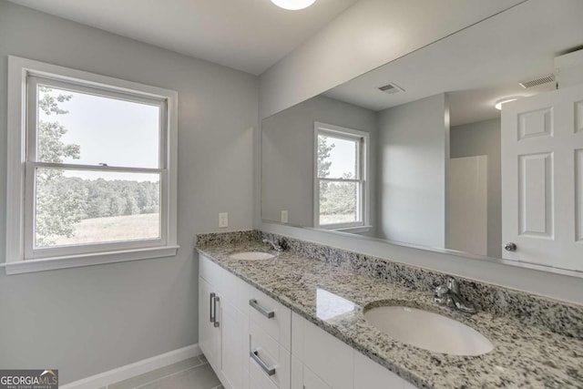 bathroom featuring double vanity, a sink, visible vents, and baseboards