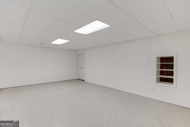 unfurnished room featuring a paneled ceiling, built in shelves, and baseboards