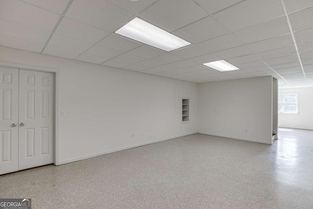 unfurnished room with speckled floor, a drop ceiling, and baseboards