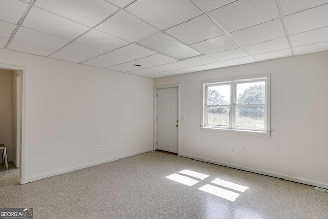 empty room with a drop ceiling and baseboards