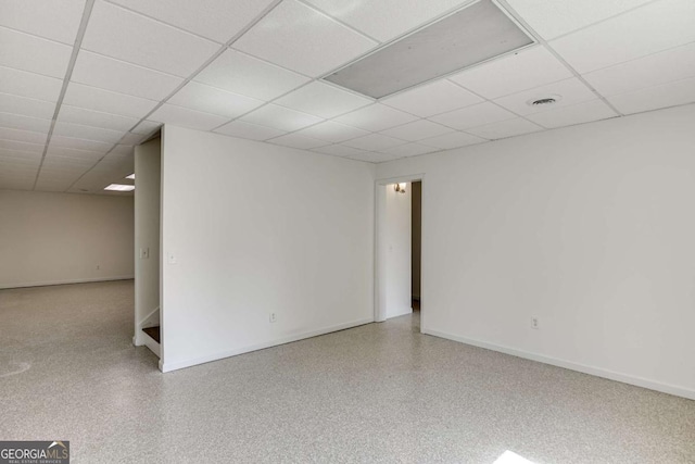 basement featuring visible vents, a paneled ceiling, and baseboards