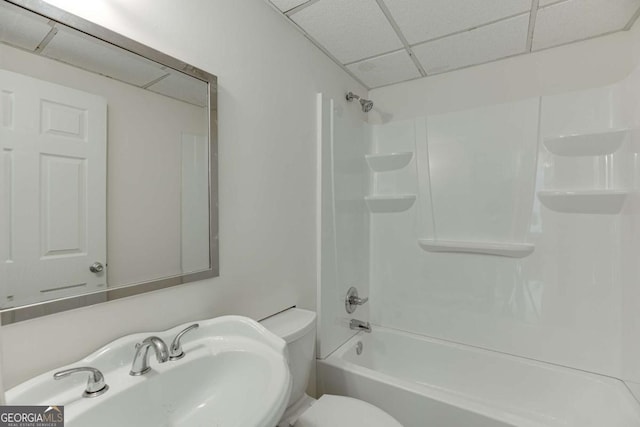 full bath with toilet, a paneled ceiling, and a sink