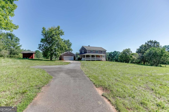 view of front of home with a detached garage, an outdoor structure, and a front yard