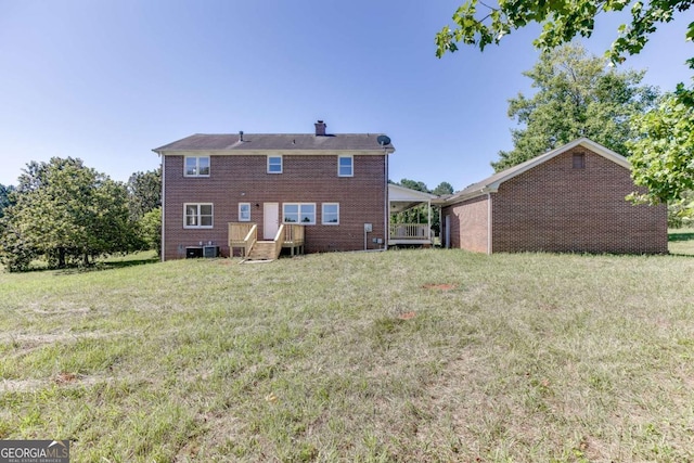 back of property featuring a yard, brick siding, a chimney, and central air condition unit