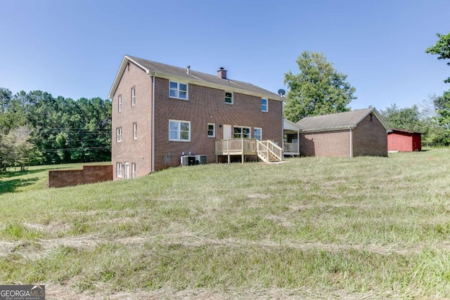 back of house with a chimney, a deck, cooling unit, a yard, and brick siding