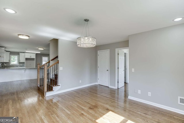 unfurnished room featuring light wood-style flooring, stairway, and baseboards