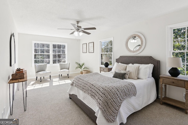 carpeted bedroom featuring a textured ceiling, a ceiling fan, and baseboards