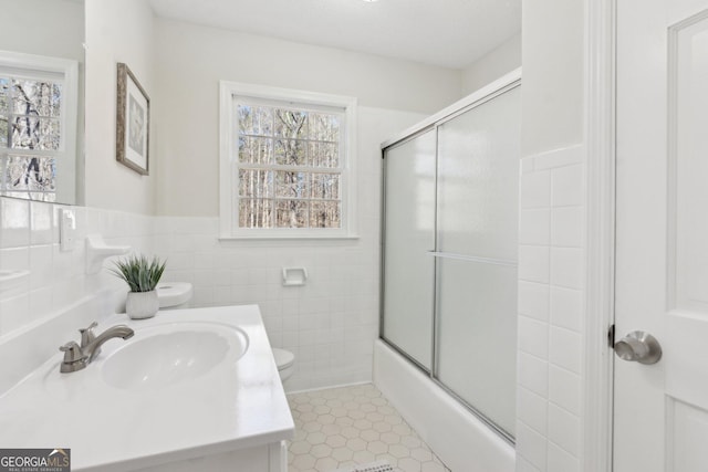 full bath with toilet, a wainscoted wall, tile patterned floors, vanity, and tile walls