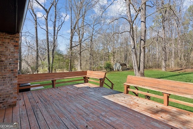 wooden deck with a lawn and a wooded view