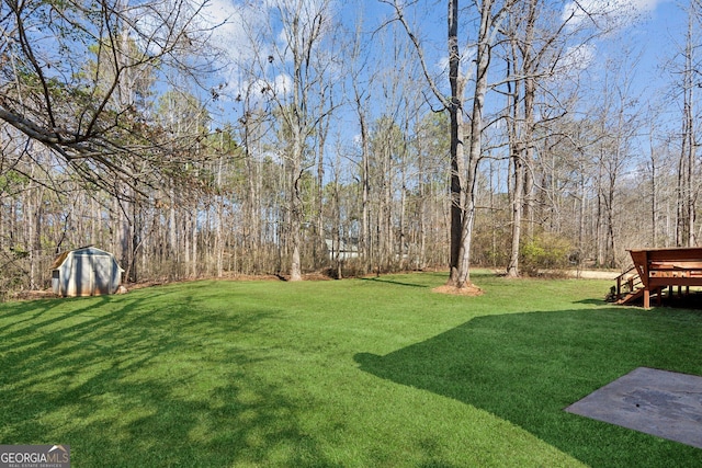 view of yard featuring an outbuilding, a wooded view, and a shed