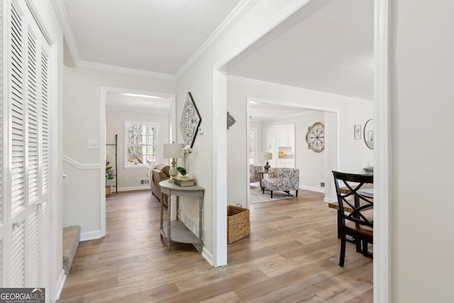 entryway with crown molding, a textured ceiling, baseboards, and wood finished floors