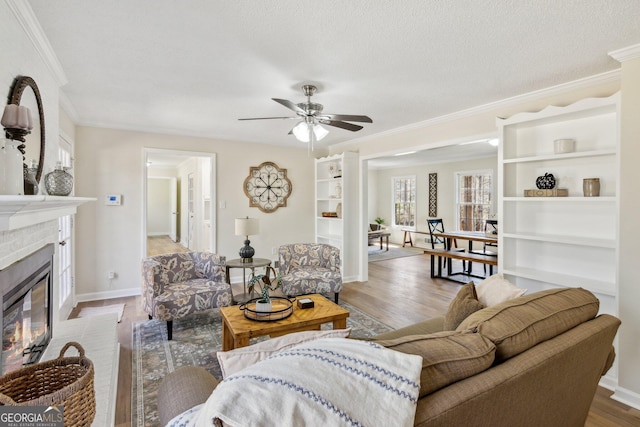 living room with baseboards, light wood-type flooring, a brick fireplace, and crown molding