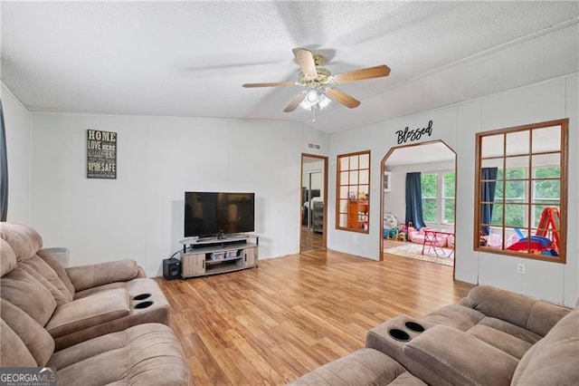 living room featuring a ceiling fan, visible vents, a textured ceiling, and light wood finished floors