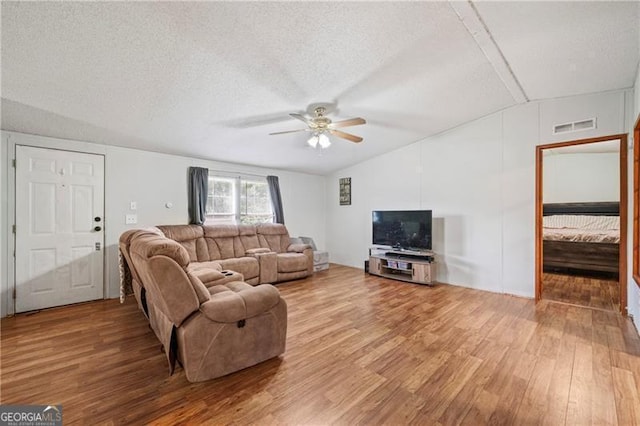 living area featuring a ceiling fan, visible vents, a textured ceiling, and wood finished floors