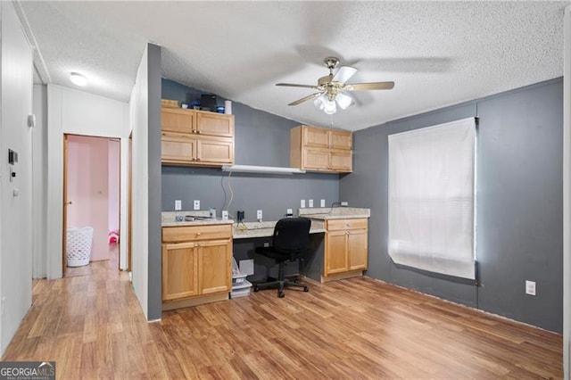 office featuring light wood finished floors, a ceiling fan, lofted ceiling, a textured ceiling, and built in desk