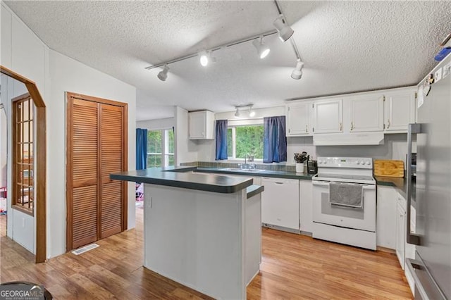 kitchen featuring under cabinet range hood, a sink, light wood-style floors, dark countertops, and white electric range oven