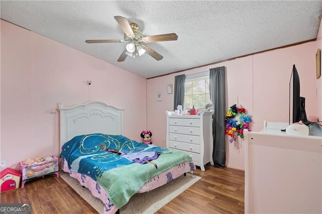 bedroom with a ceiling fan, a textured ceiling, and wood finished floors