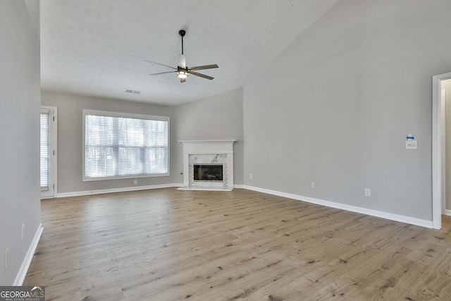 unfurnished living room featuring a fireplace, wood finished floors, visible vents, baseboards, and a ceiling fan