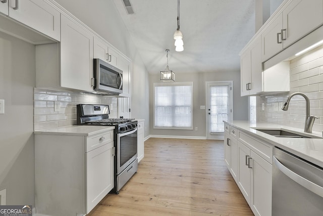 kitchen featuring light wood finished floors, white cabinetry, appliances with stainless steel finishes, and a sink