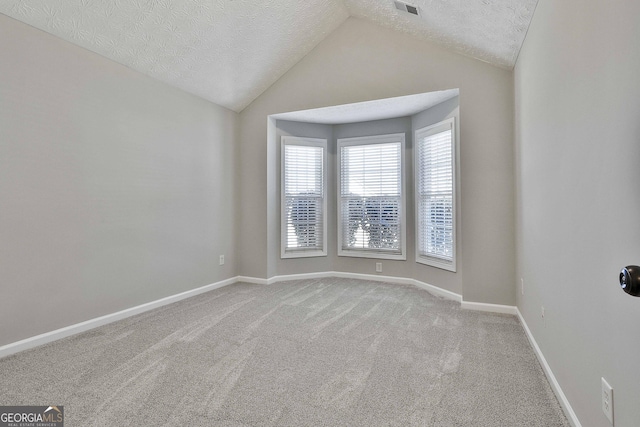 carpeted empty room featuring visible vents, vaulted ceiling, a textured ceiling, and baseboards