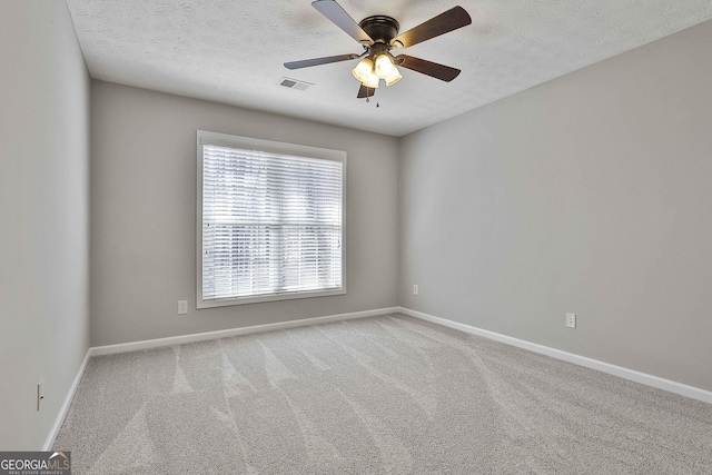 carpeted spare room with a ceiling fan, visible vents, a textured ceiling, and baseboards