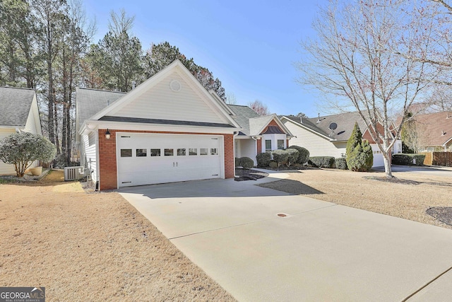 single story home with concrete driveway, brick siding, an attached garage, and central AC unit