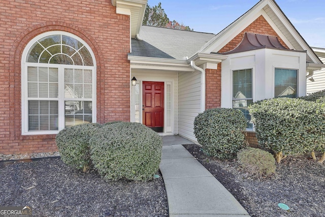 entrance to property with brick siding and roof with shingles