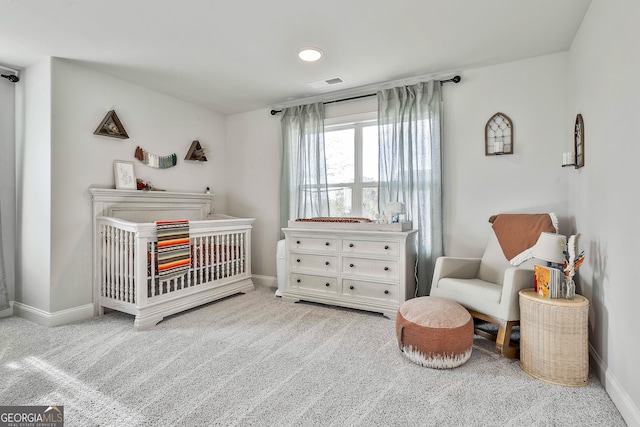 carpeted bedroom with visible vents, a crib, and baseboards