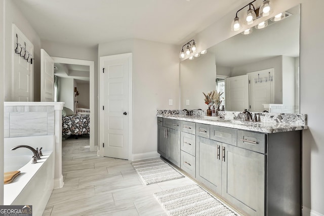 full bath with a bath, a sink, ensuite bathroom, and double vanity