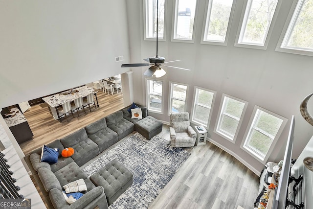 living area with a towering ceiling, wood finished floors, and visible vents