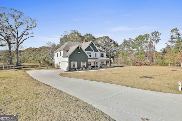 view of front facade with an attached garage, fence, driveway, and a front lawn