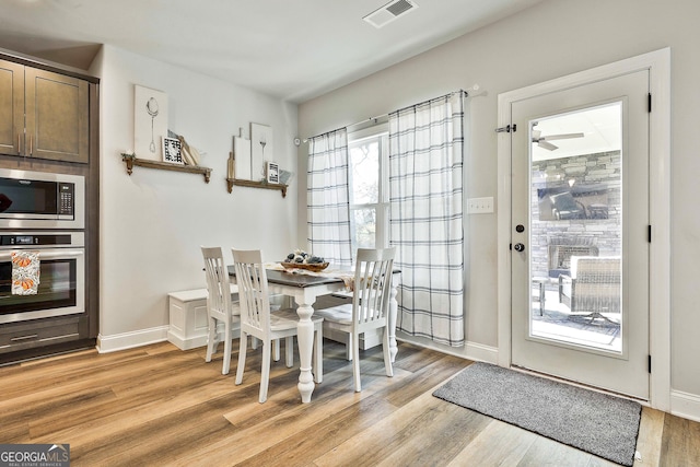 dining space with baseboards, visible vents, and light wood finished floors