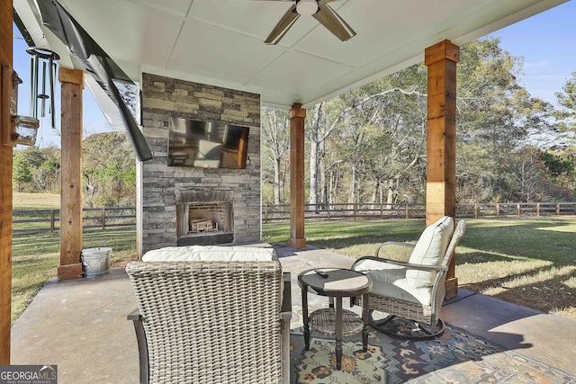 view of patio featuring a fenced backyard, an outdoor stone fireplace, and ceiling fan