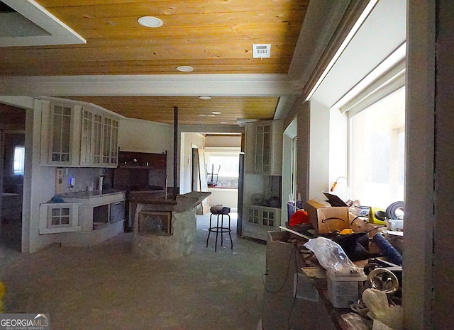 kitchen with glass insert cabinets, wood ceiling, and visible vents