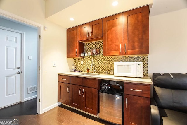 bar with baseboards, visible vents, white microwave, a sink, and backsplash