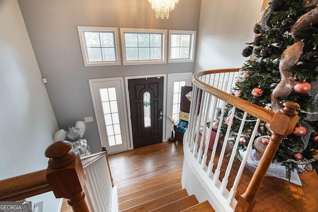 foyer with a towering ceiling, hardwood / wood-style flooring, and an inviting chandelier