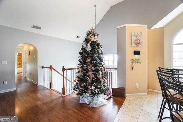 dining space featuring arched walkways, visible vents, baseboards, and wood finished floors