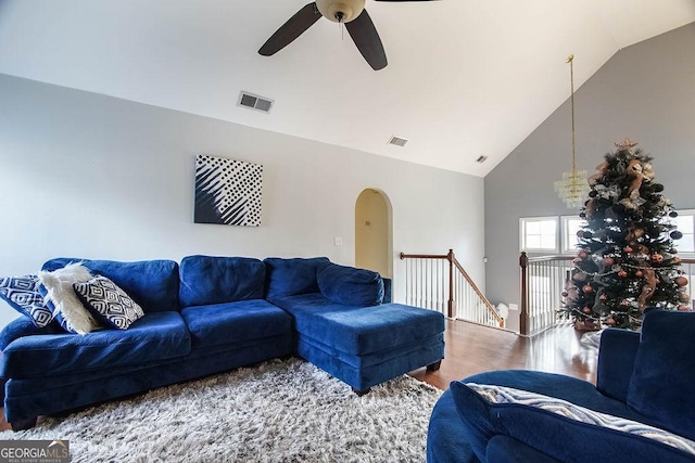 living room featuring high vaulted ceiling, arched walkways, visible vents, and wood finished floors