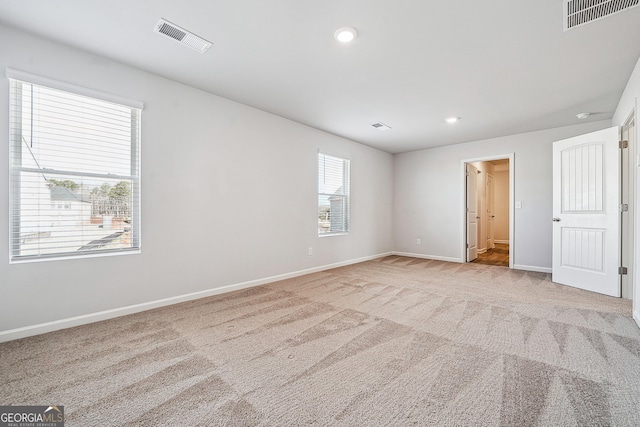 carpeted spare room featuring baseboards, visible vents, and recessed lighting