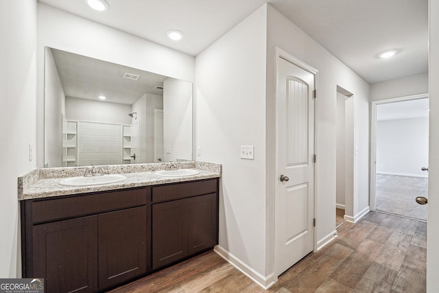 bathroom with double vanity, a sink, baseboards, and wood finished floors